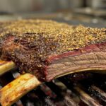 A rack of perfectly seasoned beef ribs on a grill.