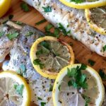 Fresh fish with lemon slices on a wooden cutting board